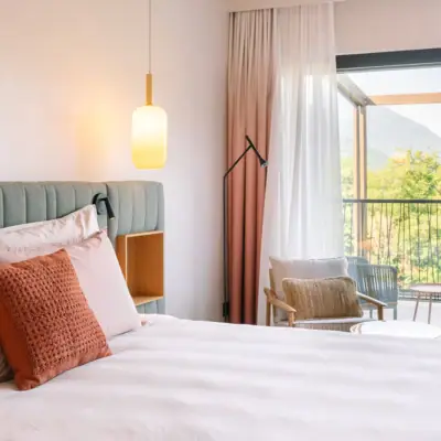 Zimmer mit Gartenblick Ein Bett mit Kissen und einer Lampe in einem Zimmer mit Balkon.