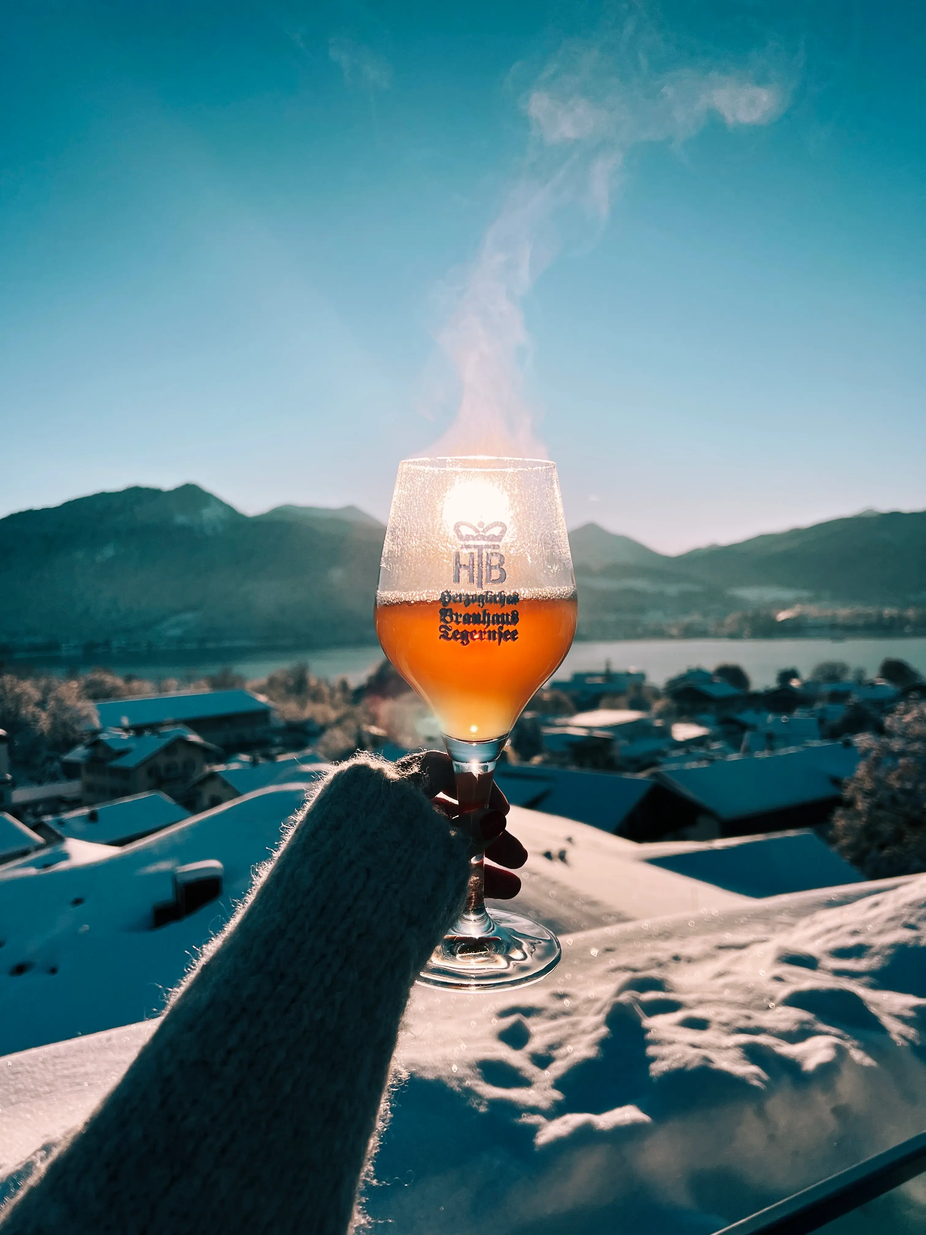 Tegernsee in winter A hand is holding a glass of wine, from which smoke is rising.