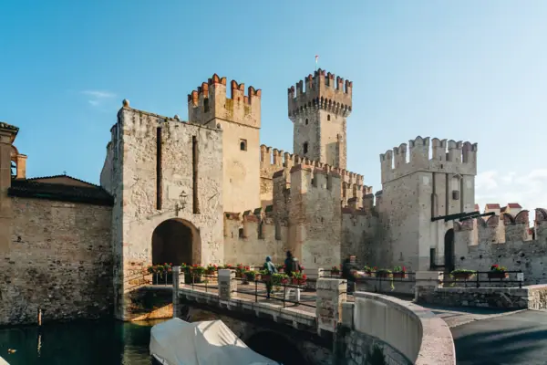 Sirmione A castle with a bridge and a body of water.