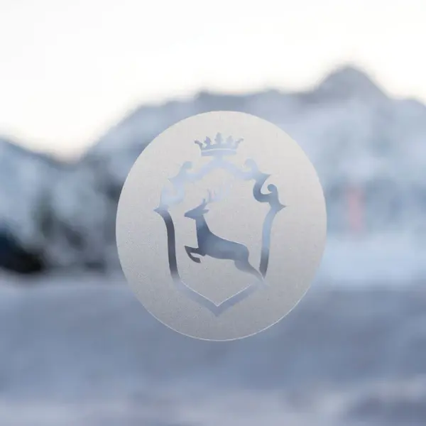 Logo of the Ifen Hotel Kleinwalsertal in foil on a window in front of a snow-covered mountain backdrop.