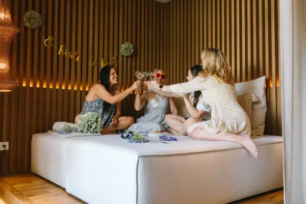 Gruppe von Freundinnen stößt in einer stilvollen SPA-Suite mit Getränken an.
