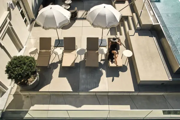 Woman sitting on a deck chair outdoors under an umbrella.
