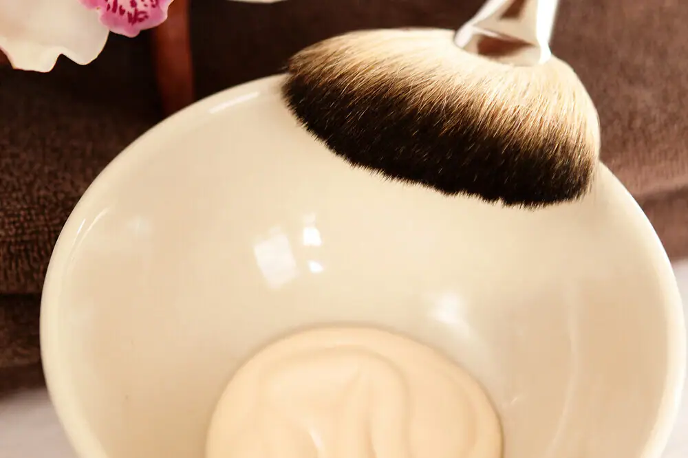 A brush resting on a bowl filled with white liquid.