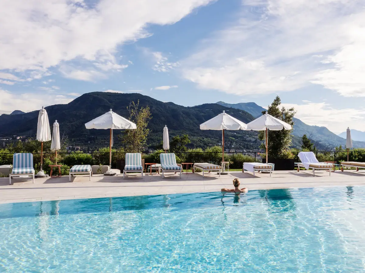 A holiday on Lake Garda with A-ROSA A person by the pool with parasols and sun loungers.
