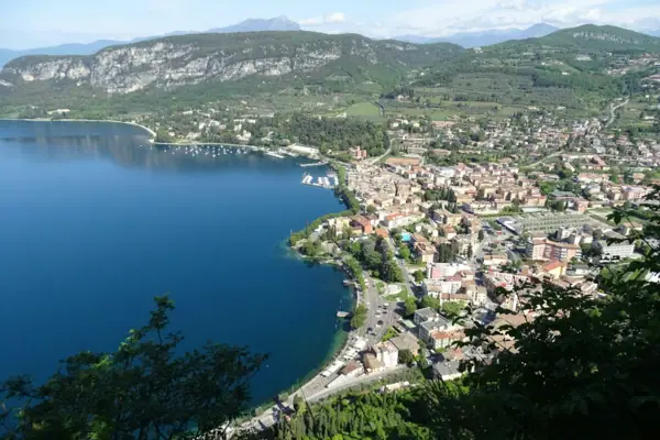 Garda A bird’s-eye view of a town on the banks of a body of water, with mountains in the background.