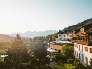 A building surrounded by trees with mountains in the background in the morning haze.