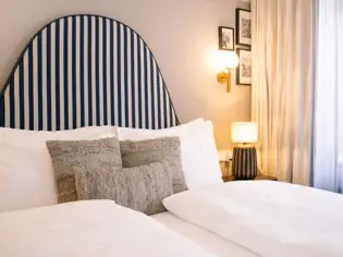 A cozy hotel bedroom featuring a neatly made bed with plush pillows and a bedside lamp.