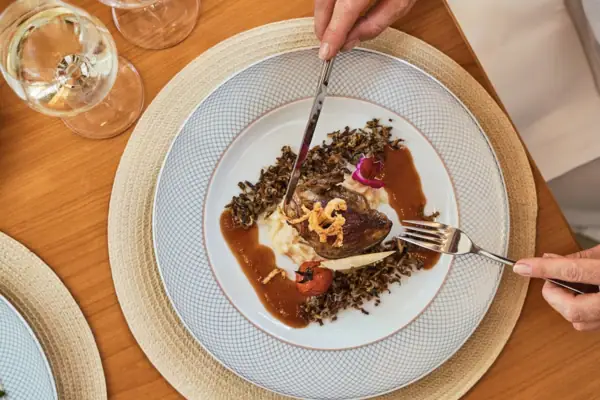 A person eating a meal from a plate with tableware.