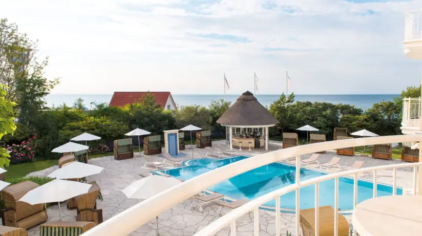 Balcony view of pool with chairs and umbrellas on the beach.