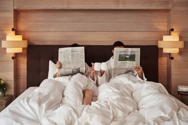 A man and a woman are reading in bed.