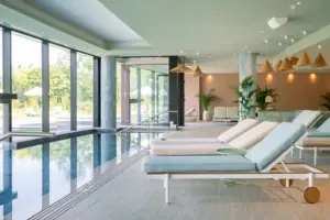A swimming pool with sun loungers in the foreground and another swimming pool in the background.