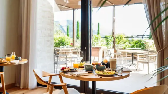 Table with food in a stylishly furnished dining room, near a window.