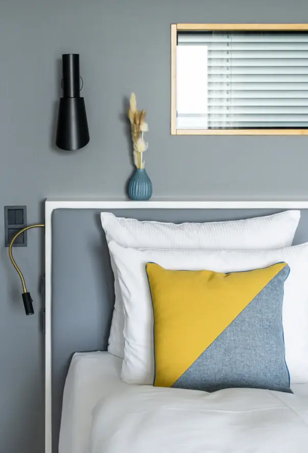 A bed with a yellow and gray pillow.