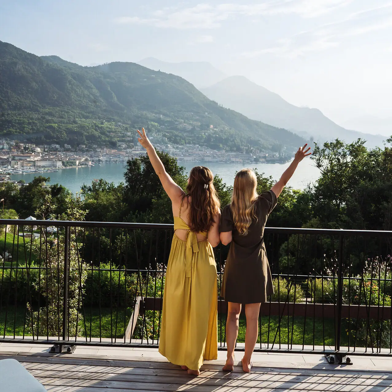 Two women standing on a balcony overlooking a body of water.