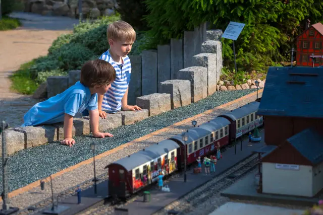 Two boys are looking at a model railway in Wernigerode Miniature Park.