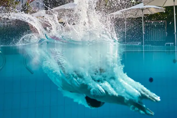 A person diving into an outdoor swimming pool.