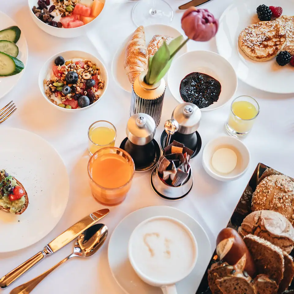 A table set with plates of various foods and drinks.