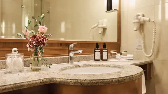 Bathroom with washbasin and a vase of flowers.