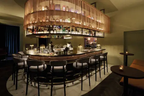 A U-shaped hotel bar with lots of high chairs around the counter.