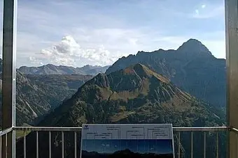 Ein Bergmassiv mit einem Schild im Vordergrund.