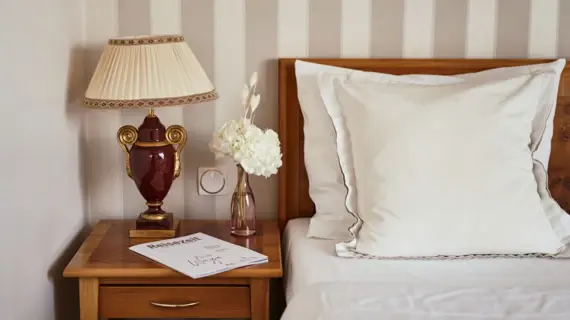 A lamp on a bedside table next to a bed.