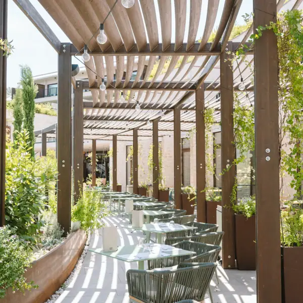 Überdachte Terrasse mit Tischen und Stühlen.