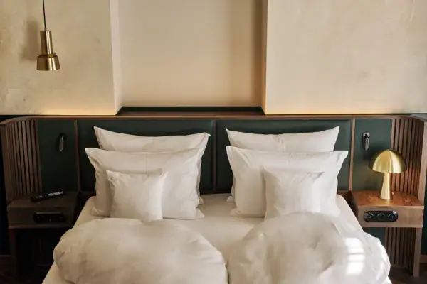 A bed with white pillows and a green headboard.