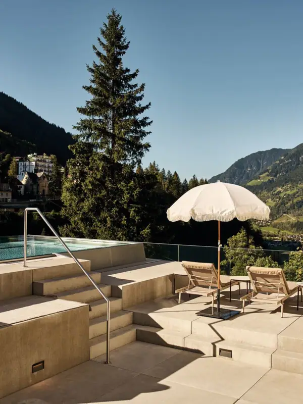 Ein Pool mit Sonnenschirmen und Liegestühlen an einem sonnigen Tag.