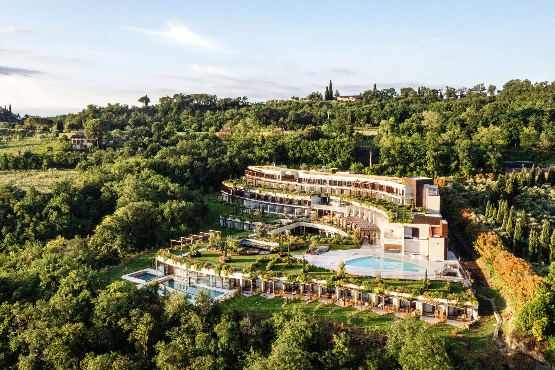 Aerial view of A-ROSA Lake Garda surrounded by lush greenery with pool and panoramic views of the lake.