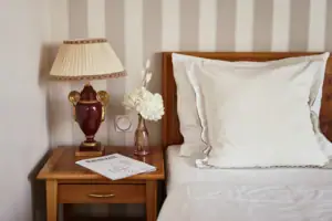 A lamp on a bedside table next to a bed.