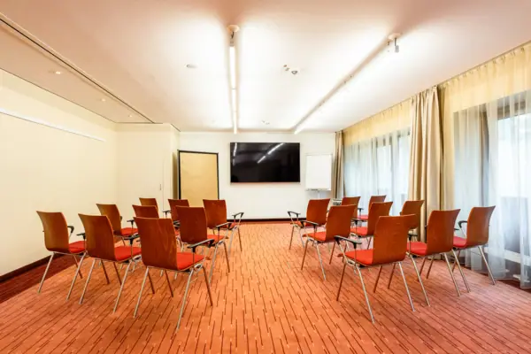 A room with chairs and a screen at A-ROSA Travemünde.
