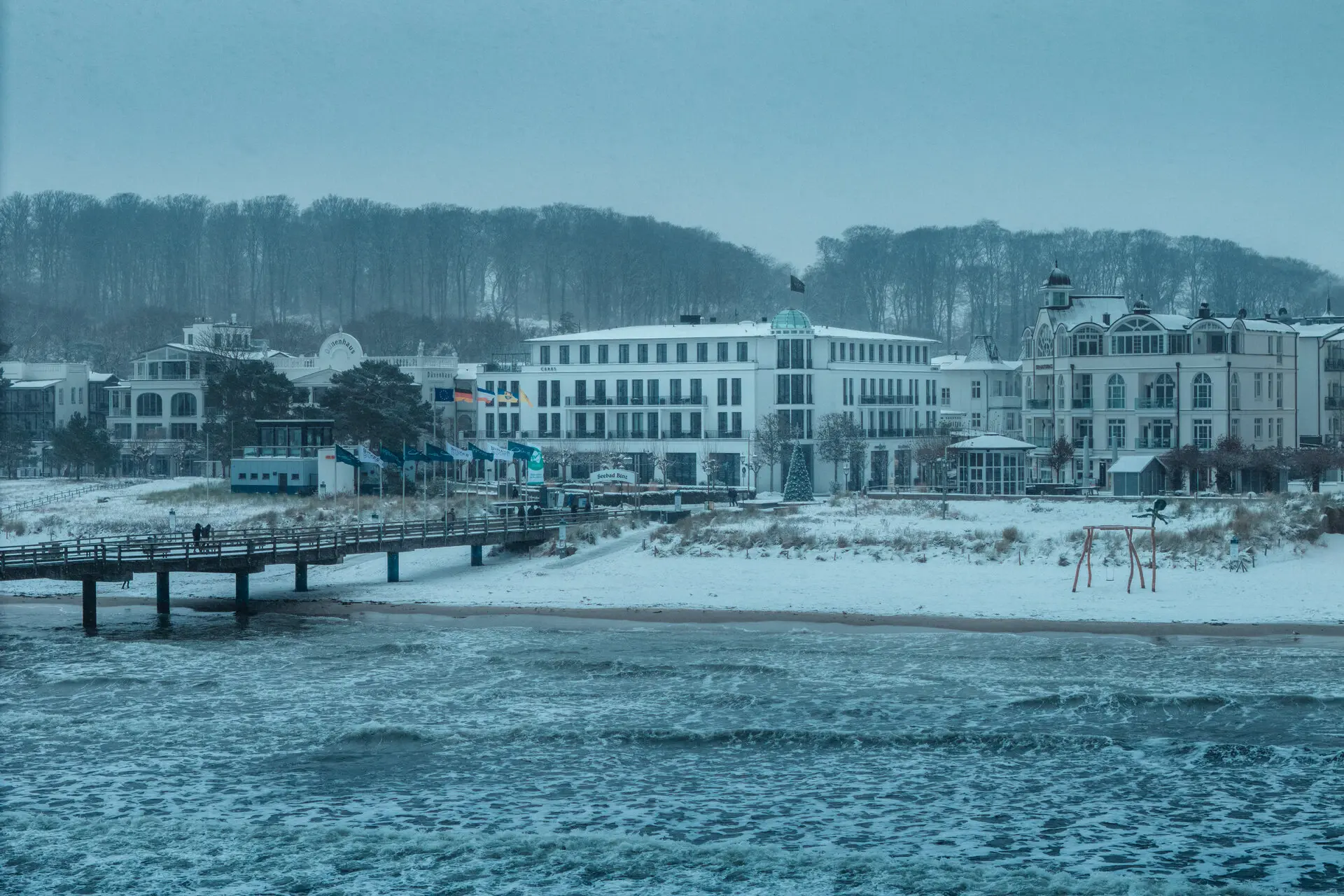 A snow-covered beach with buildings in winter.