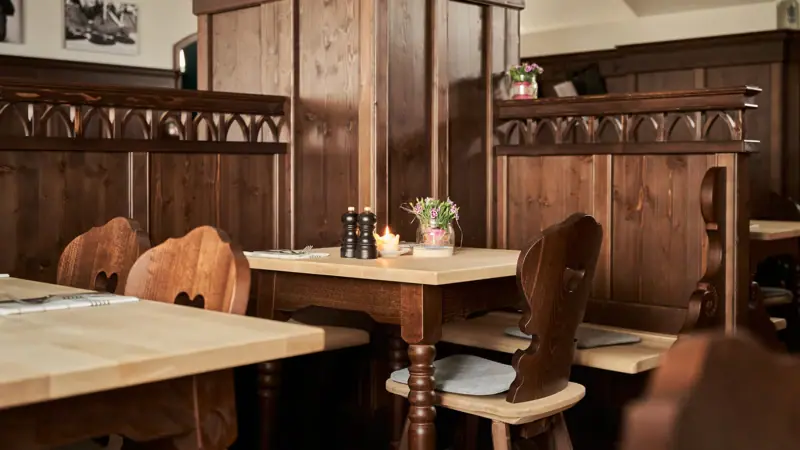 A table with candles and chairs in a room with wood-panelled walls.