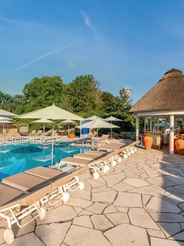 A swimming pool with lounge chairs and umbrellas under a clear sky.