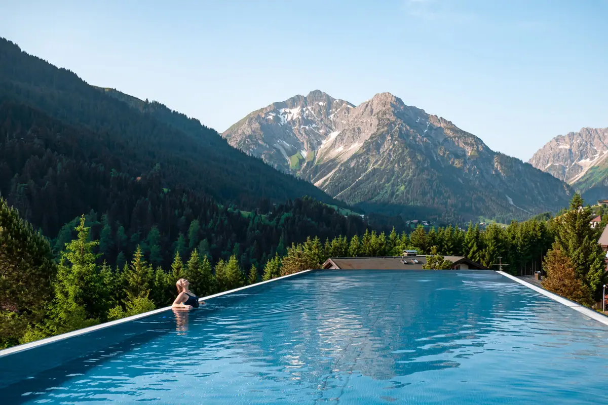 A person in a swimming pool with mountains in the background.
