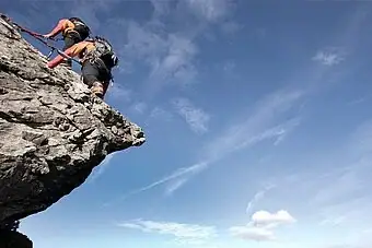 Eine Person beim Klettern auf einem Felsen unter freiem Himmel.
