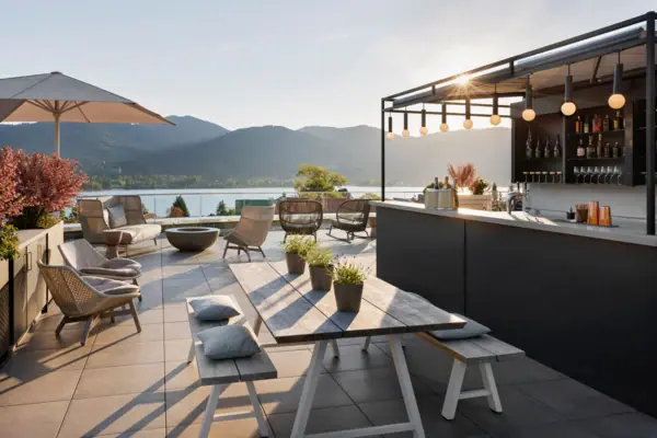 The terrace at the A-ROSA Tegernsee, featuring a bar and tables, as well as spectacular views of Lake Tegernsee and the mountains.