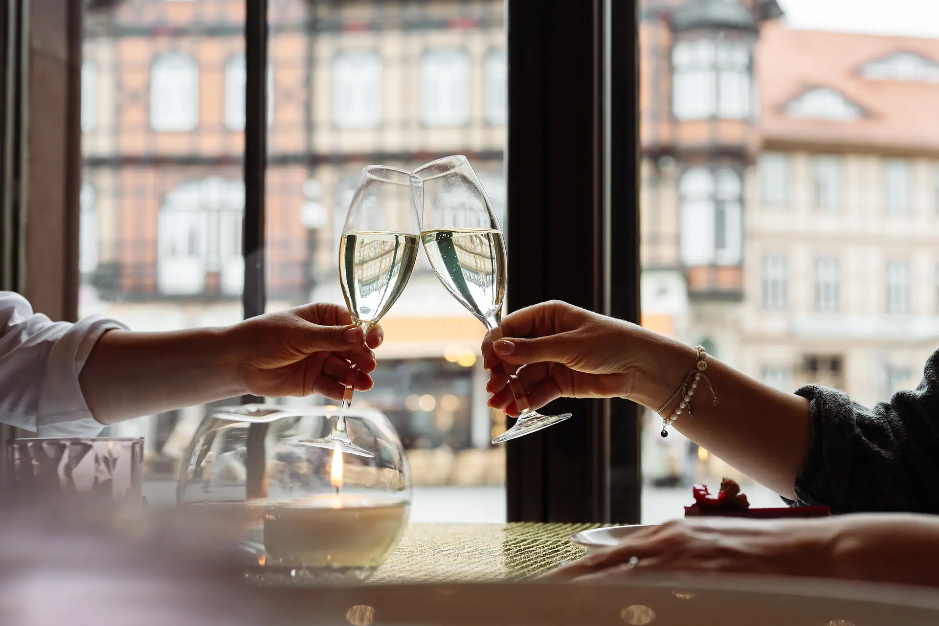Two hands clink wine glasses.