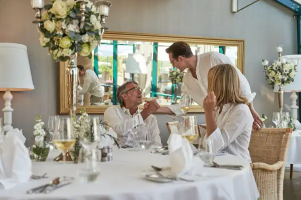 A group of people sitting at a table adorned with floral arrangements and tableware.