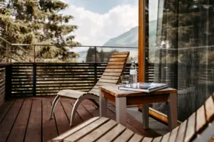 A chair and a table on a wooden deck outdoors.