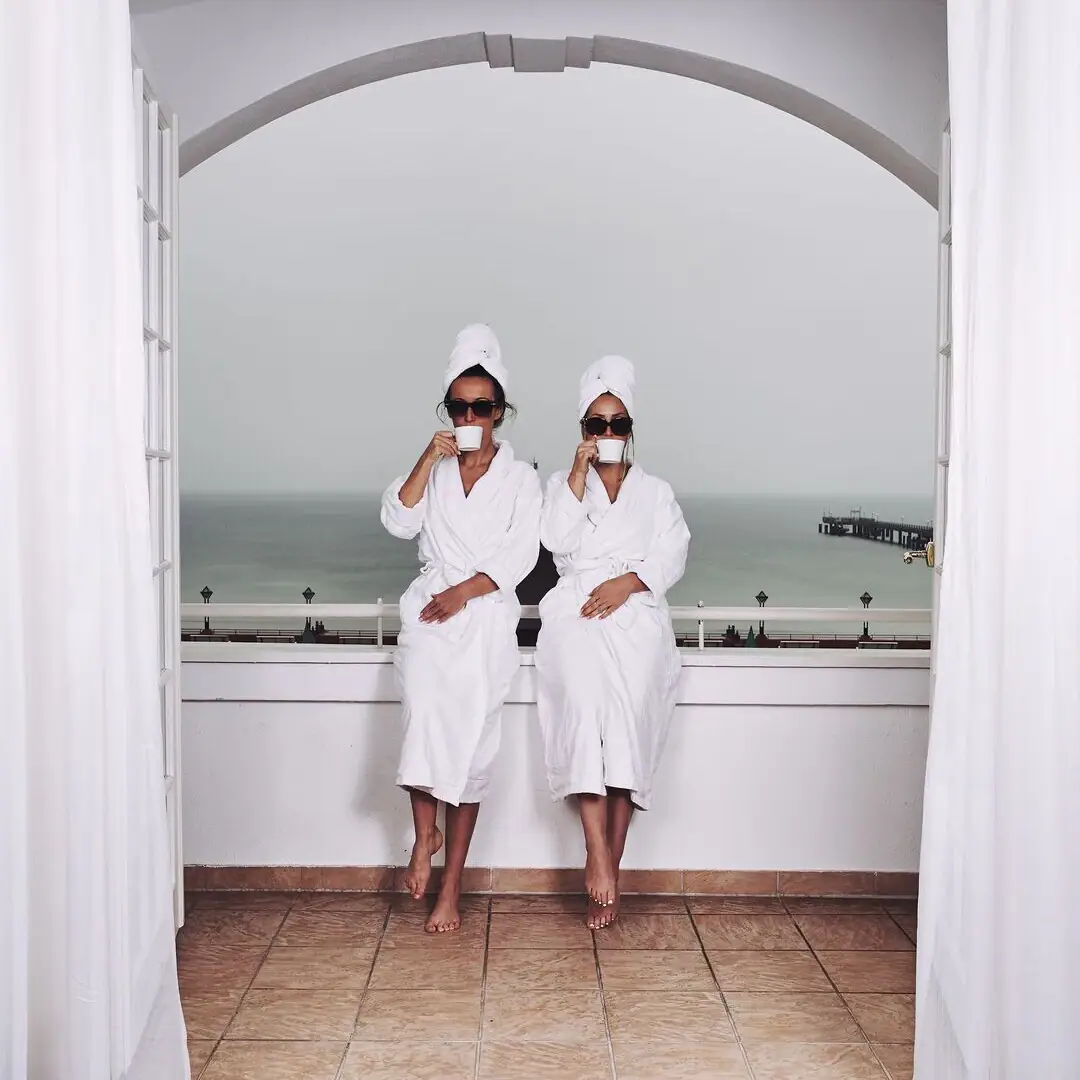 Day SPA Two women in white robes and towels sitting on a window sill.