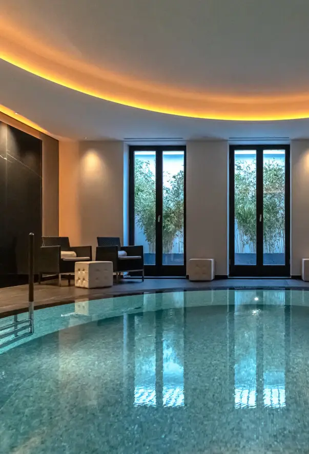 Large round indoor swimming pool in a hotel with elegant interior design.