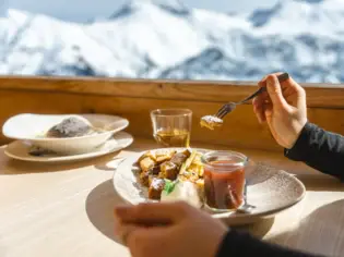 A person eating a meal using a fork at a table.