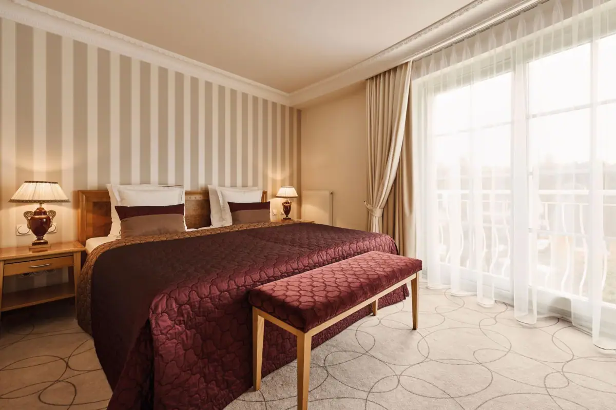 A bed with a bench in a room featuring striped walls.