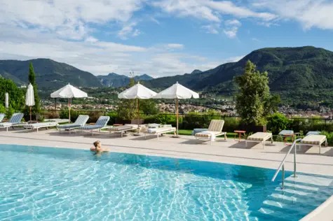 Person in the pool surrounded by parasols and sun loungers.