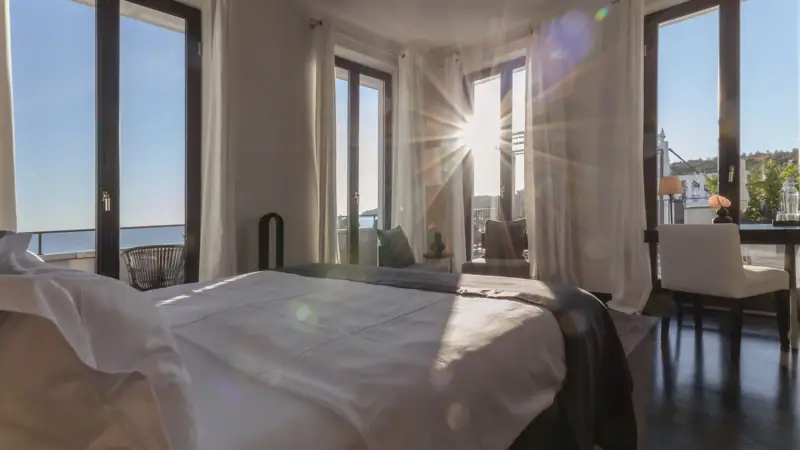A well-appointed bedroom with a neatly made bed and large windows.