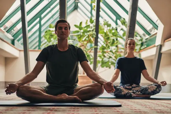A man and a woman are sitting on yoga mats.