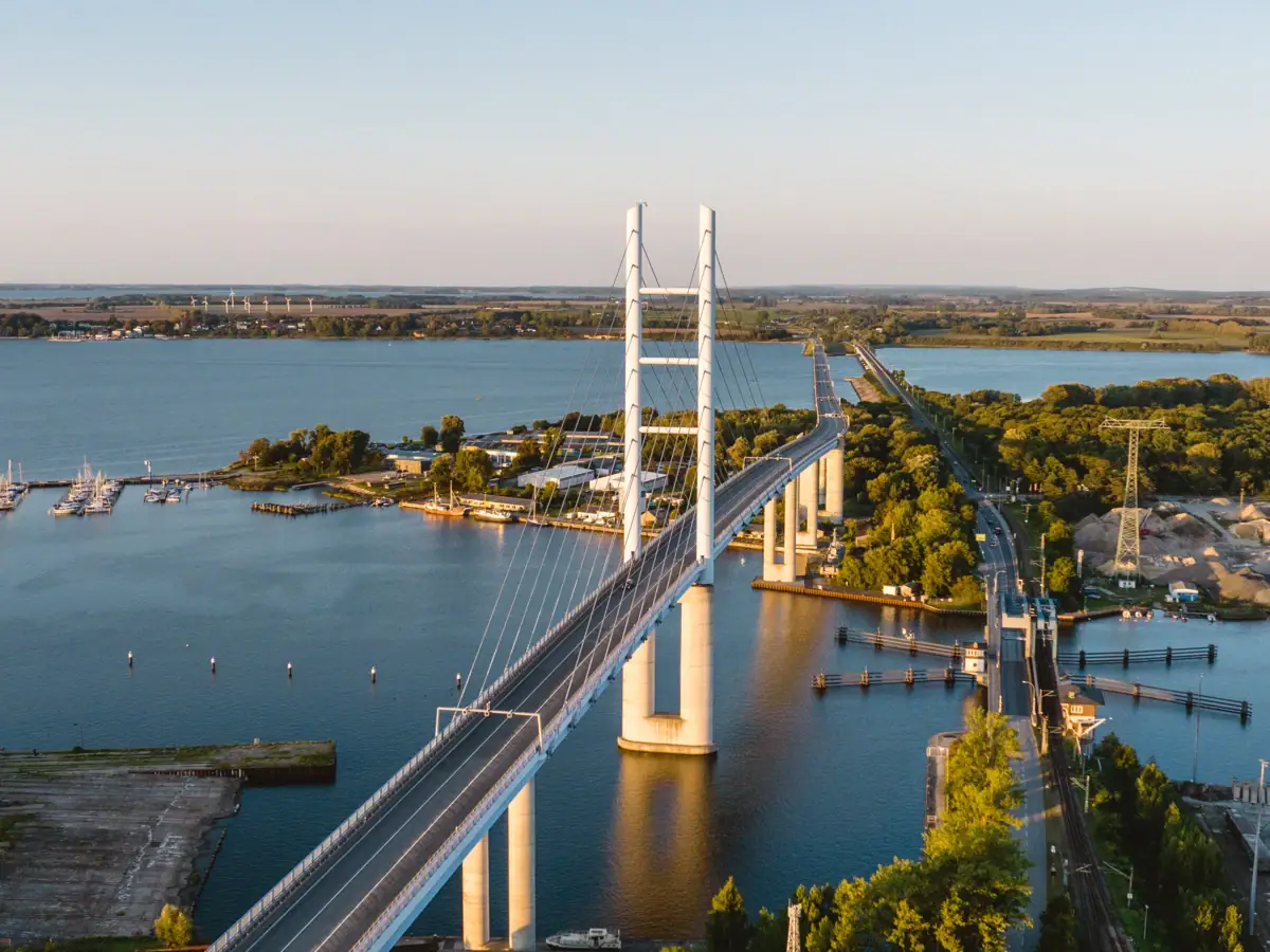Brücke über Wasser mit Bäumen und Stadt im Hintergrund