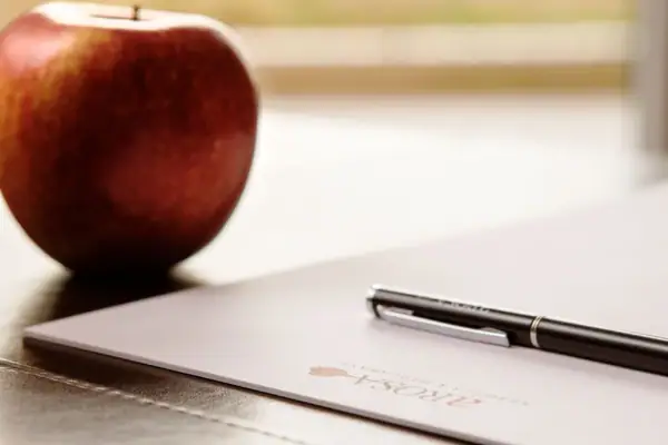 Tagung Detail Ein Stift auf einem Blatt Papier neben einem Apfel.