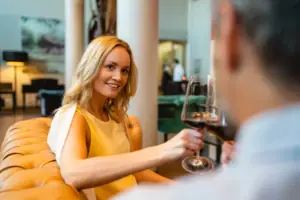 Frau hält ein Weinglas und lächelt.